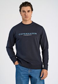 Marine Sweatshirt mit Rundhalsausschnitt, langen Ärmeln und einem hellblauen Grafikdruck "COPENHAGEN LINDBERGH" auf der Vorderseite. Strukturierter Stoff.