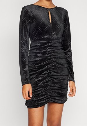 Schwarzes Samtkleid mit langen Ärmeln, das über einen Schlüsselaugen-Ausschnitt, geraffte Seiten und silberne punktuelle Verzierungen verfügt.
