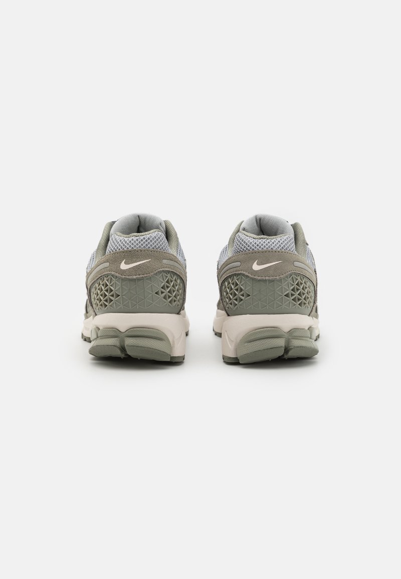 Sportowe buty Nike z siateczki i zamszu w kolorach szarym i beżowym, z teksturowanym wzorem oraz charakterystycznym logo swoosh na pięcie.