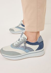 Sneaker blu chiaro e grigio con dettagli zip, realizzati in suede e materiali lisci; presentano un design stratificato e una suola testurizzata.