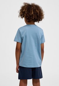 Lyseblå bomulds T-shirt med korte ærmer og rund halsudskæring, parret med navy shorts. Blød tekstur, enkelt design og ingen synlige mønstre.