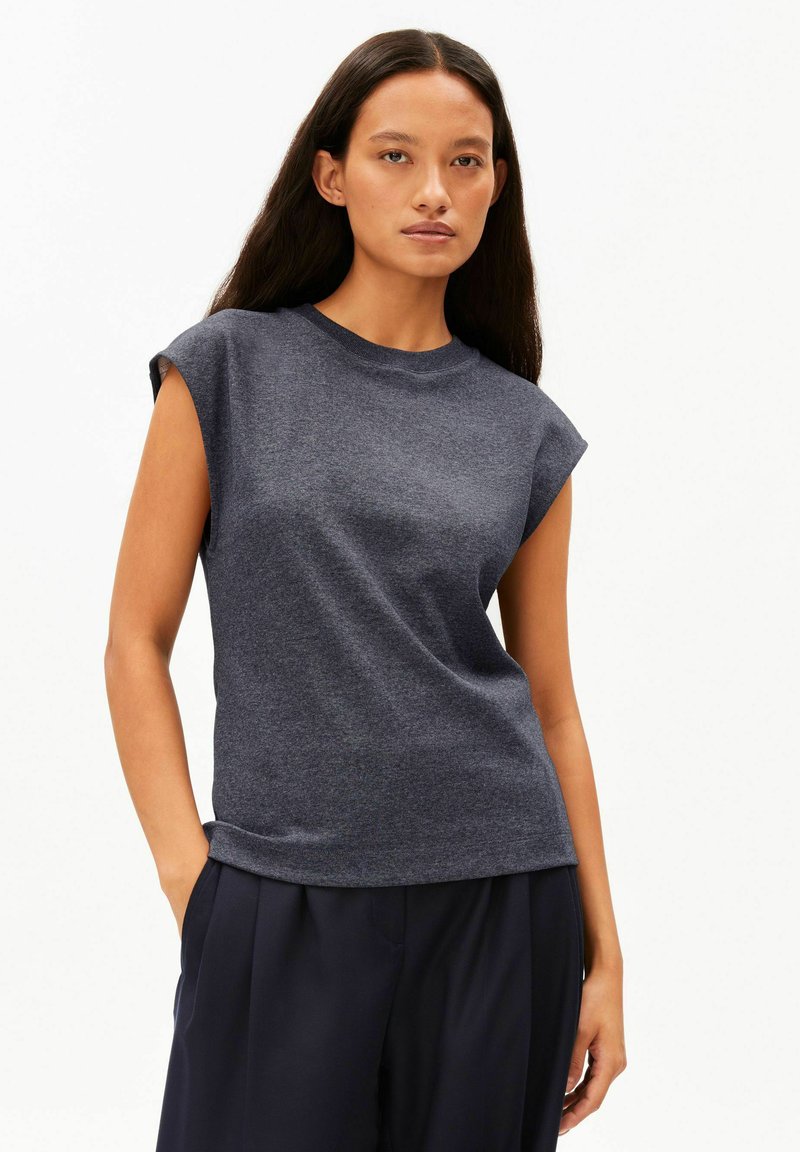 Donkergrijs mouwloos shirt met een ronde hals en een relaxte pasvorm. Gemaakt van zachte, gestructureerde stof, gecombineerd met een donkere broek.