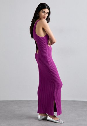 Robe maxi en tricot côtelé violet ajustée avec un dos décolleté, des fentes latérales et des bretelles larges. Portée avec des ballerines en argent métallisé.