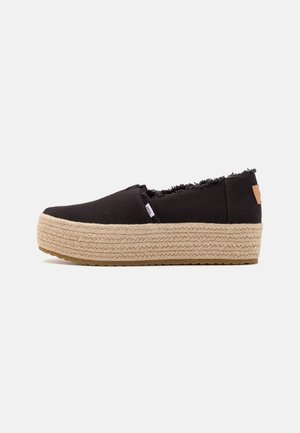 Espadrille noire à enfiler avec bords effilochés et semelle plateforme épaisse en jute tressé, sur fond blanc.