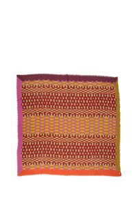 Coperta intrecciata multicolore con motivi geometrici in rosso, giallo, viola e rosa. I bordi sono frangiati per aggiungere texture.