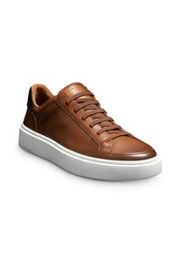Baskets en cuir marron avec des panneaux latéraux perforés, des lacets plats et un dos contrastant noir. Elles disposent d'une semelle en caoutchouc blanc épais pour un bon amorti.