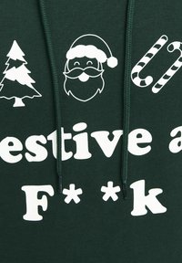Icônes de sapin de Noël blanc, visage du Père Noël et canne en bonbon au-dessus d'un texte partiellement visible sur un tissu vert foncé avec deux cordons verts.