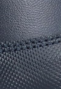 Material texturizado de color azul oscuro con un acabado mate. Presenta pequeños patrones piramidales y costuras visibles a lo largo de la costura.