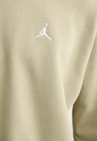 Oliven grøn sweatshirt i stof med et hvidt broderet Jumpman-logo på brystet. Blød tekstur med ribbet halsudskærning.