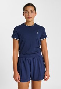 Marinblå t-shirt med vitrandig halsringning och ärmar, kombinerad med matchande marinblå shorts med resår i midjan och veck.