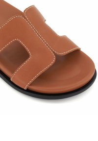 Bruine leren sandaal met open teen, met een uitsnedeontwerp en contrasterend witte stiksels. Zwarte rubberen zool voor grip.
