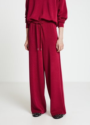 Weit geschnittene Jogginghosen in einem lebendigen Burgunderrot, mit elastischem Bund und Kordelzug, gefertigt aus einem weichen, leichten Stoff.