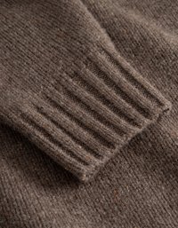Tissu de pull en tricot marron avec un détail de poignet côtelé. Texture douce avec des éclats de couleur tout au long. Design globalement ample et confortable.
