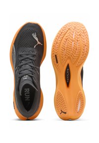 Scarpe da corsa con una tomaia in rete grigia, suola arancione, dettagli in gomma nera e un modello di battistrada testurizzato per grip e supporto.