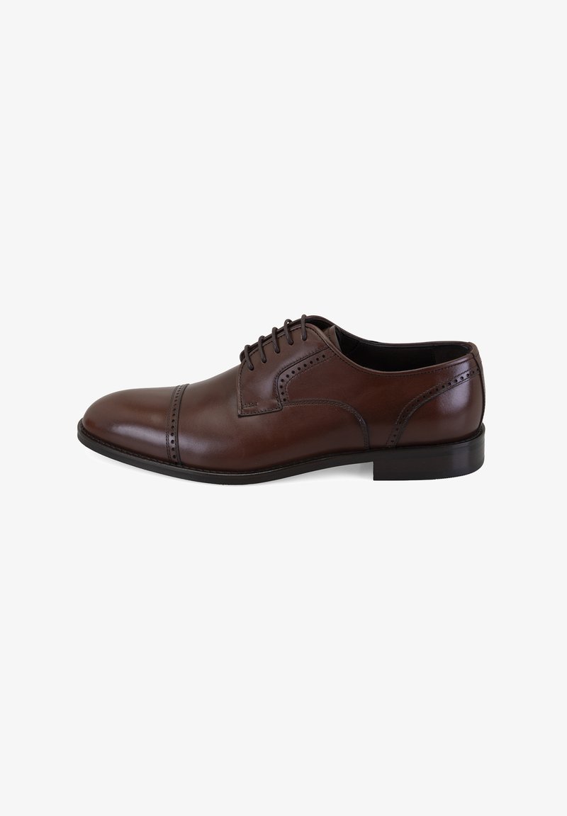 Bruine leren Oxford schoen voor mannen met brogue details en gesloten veters, bekeken vanaf de zijkant op een witte achtergrond.