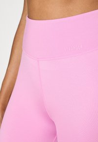 Leggings roz cu talie înaltă, dintr-un material neted, cu un logo subtil "STRONGER" și cusături plate pentru confort și potrivire.
