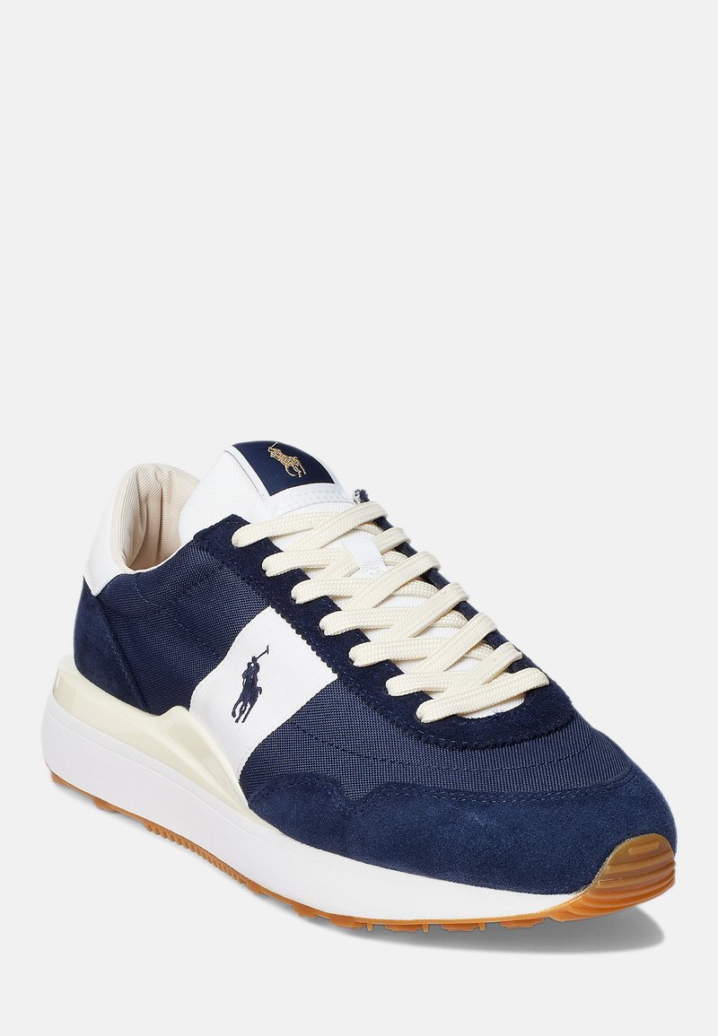 Marineblaue Wildleder- und Canvas-Sneaker mit cremefarbenen Schnürsenkeln, weißem Seitenstreifen und goldfarbenem Logo auf der Zunge. Gummisohle mit strukturierten Details.