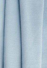 Lyseblåt ribbet stof med vertikale riller og bløde folder, der viser tekstur og subtile skygger.