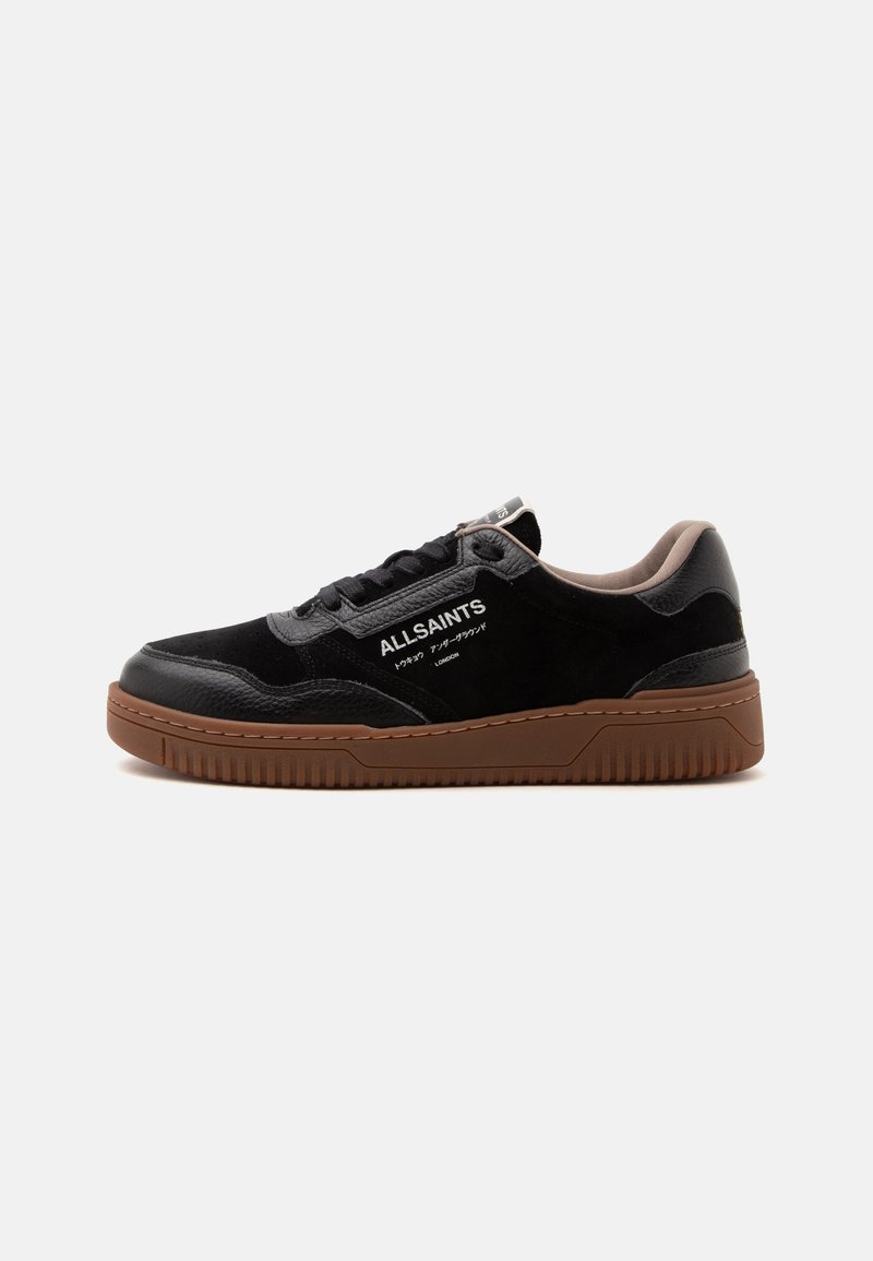 Μαύρο sneaker AllSaints χαμηλού τύπου με καφέ λαστιχένια σόλα και λευκό κείμενο λογότυπου στο πλάι, εμφανίζεται από την εξωτερική πλευρά.