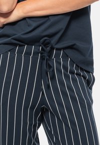 Pantaloni a righe blu navy in morbido tessuto, con strisce verticali bianche, vita con cordino e vestibilità rilassata per il massimo comfort.
