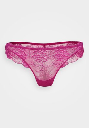 String rose en dentelle avec un motif floral, des bords festonnés et une ceinture unie. Tissu léger et semi-transparent.