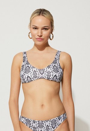 Bikini de patrón en blanco y negro con un diseño estructurado, tirantes anchos y textura suave. Acentuado con patrones simples y contrastantes.