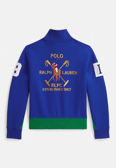 Modré mikina s dlhým rukávom so zeleným lemovaním, vyšívaným hráčom póla s prekríženými malletmi a textom „Polo Ralph Lauren RLPC Established 1967“ na chrbte.