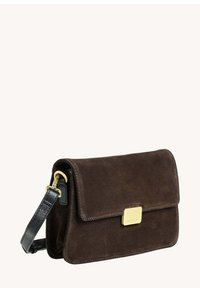 Sac à main en daim marron avec un rabat pliant, une bandoulière en cuir noir et des accents en métal doré. Texture lisse avec un design minimaliste.