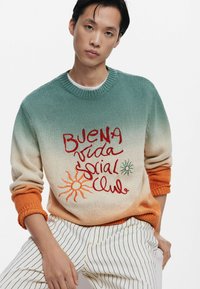 Gebreide sweater met een verloop van groen naar oranje, met rode en groene tekst en zongraphics. Geribbelde mouwen en ronde halslijn.