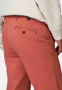 Pantalons en toile de coton corail, comportant une poche arrière avec un bouton et des coutures contrastantes. Coupe mi-haute avec une jambe droite.