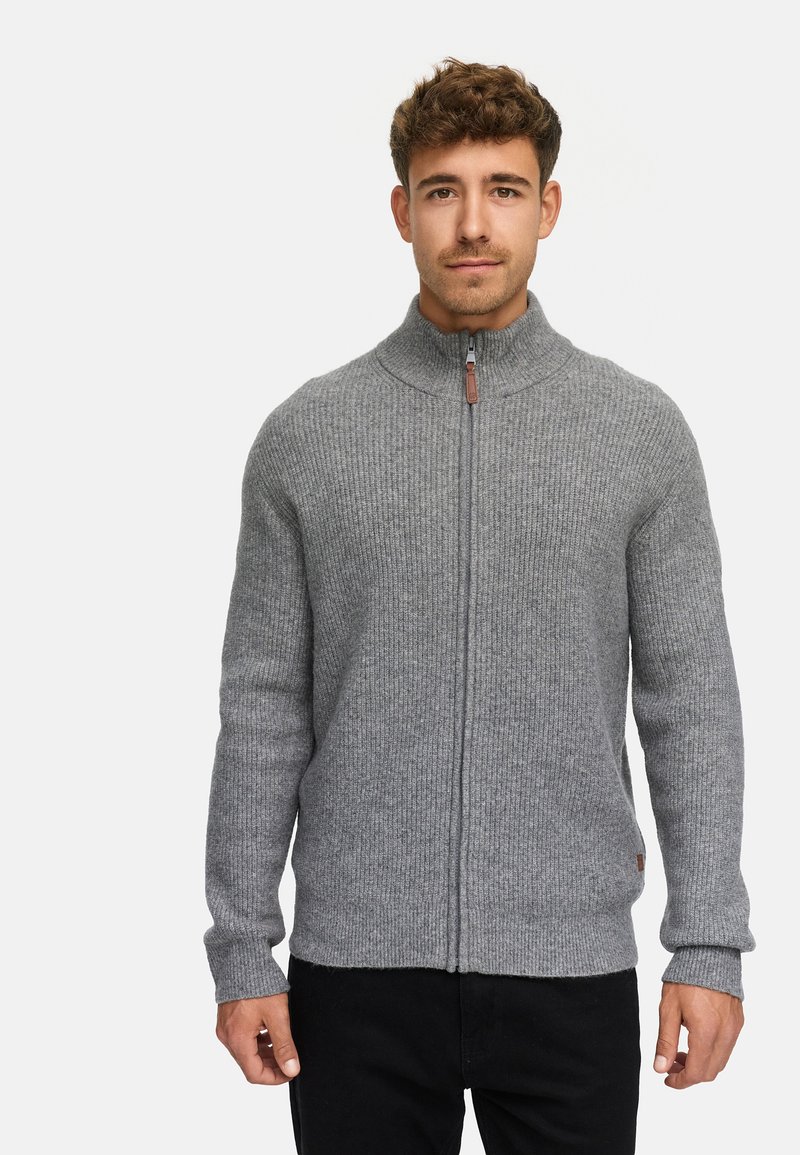Suéter gris de canalé con cuello alto y cremallera frontal. Presenta un diseño de punto texturizado y un pequeño acento de logo de cuero.