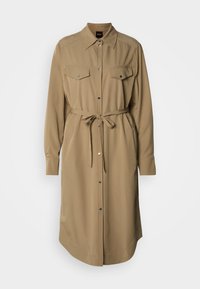 Φορεματάκι από απαλό ύφασμα σε ταμπά χρώμα με κουμπιά μπροστά, δύο τσέπες στο στήθος και ζώνη που δένει στη μέση. Μακριά μανίκια με μανσέτες με κουμπιά.