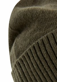 Zielona dzianinowa czapka beanie z miękkiej wełny o teksturowanym prążkowanym wzorze. Materiał wydaje się gruby i przytulny z lekko zawiniętym rondem.