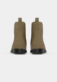 Hnědé semišové kotníkové boty s kulatou špičkou, elastickými postranními panely a černým zúženým podpatkem. Obsahují poutko pro snadné obutí a vyzutí.