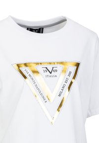 Witte katoenen t-shirt met een gouden en zilveren driehoek ontwerp met bedrukte details. Ronde hals met een soepele textuur.