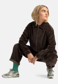 Brown corduroy zip-up jacket and matching pants; sneakers with green socks; textured fabric; relaxed fit; cuffed pants.