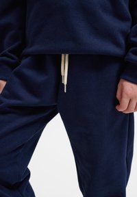 Granatowy bawełniany dres o komfortowym kroju, z ribbowanymi mankietami i off-white sznurkiem. Miękka tekstura, minimalistyczny design.