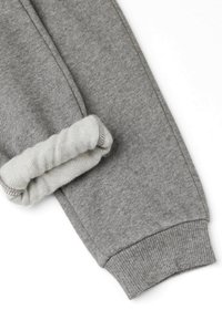 Miękkie szare dresowe spodnie z elastycznym ściągaczem u dołu, ukazujące puszyste, ocieplane wnętrze dla ciepła i komfortu.