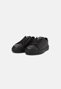 Sneakers in pelle nera con una finitura liscia, punta rotonda, suola piatta, lacci arrotondati e logo discreto sulla linguetta.