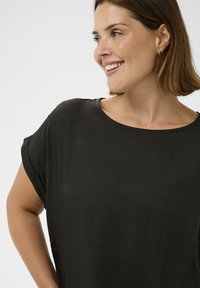 Tricou negru, cu croială lejeră, cu decolteu larg și mâneci rulate, confecționat dintr-un material fin și ușor. Design minimalist, fără motive.