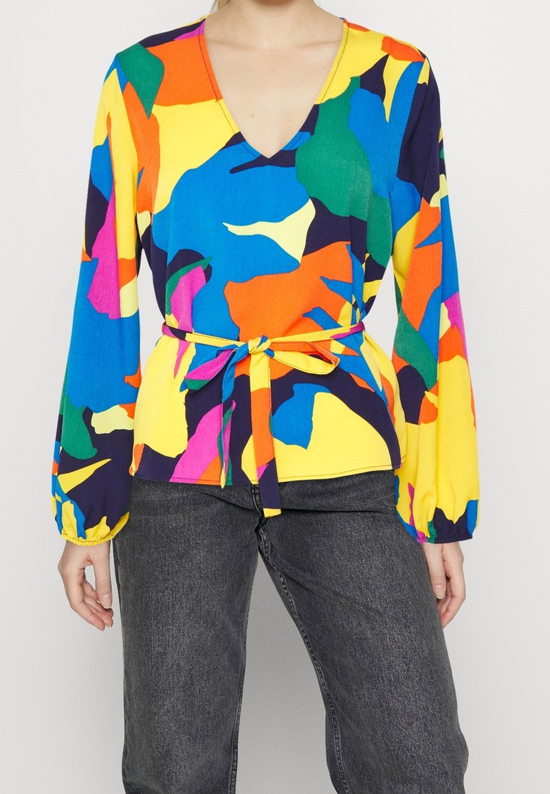 Färgglad blus med V-ringning, långa ärmar och ett knytbälte i midjan. Tillverkad av lätt material med abstrakta mönster i livliga färger.