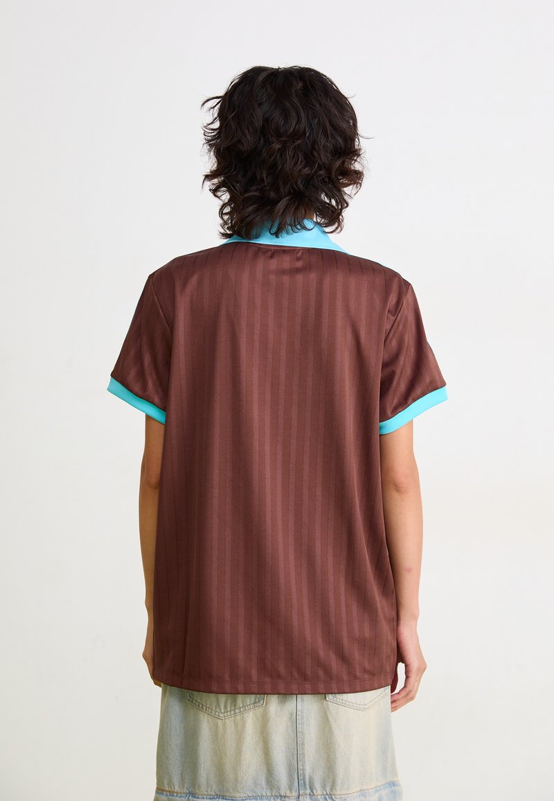 Camisa de manga corta a rayas marrón con cuello verde azulado. La tela parece suave y ligera, con líneas verticales sutiles.