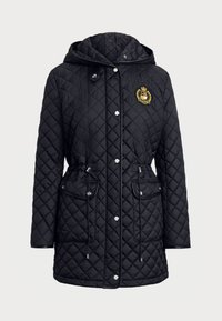 Veste matelassée noire avec capuche, ornée d'un emblème doré, poches zippées et cordons de taille ajustables. Texture lisse et design moderne.
