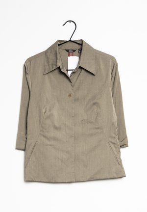 Bluzka w kolorze jasnobrązowym z kołnierzykiem, z zapięciem na guziki, z rękawami o długości 3/4 i kieszeniami po bokach. Teksturowany materiał z delikatnym wzorem. Stworzona do noszenia na co dzień.