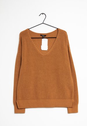 Pull marron en tricot avec col en V et manches longues suspendu à un cintre en métal noir sur fond blanc, étiquette de prix visible.