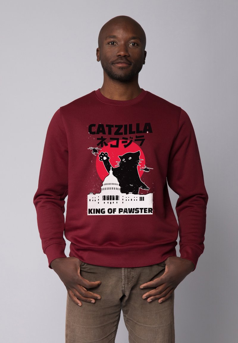 Sweatshirt bordeaux avec un design graphique représentant un chat noir, le Capitole des États-Unis, et du texte en japonais et en anglais. Matière en mélange de coton.