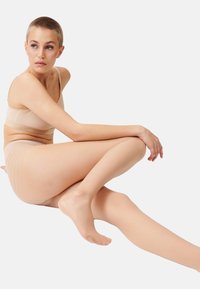 Collants nus et transparents avec une texture lisse et de subtils rayures horizontales, accompagnés d'un soutien-gorge doux assorti et de sous-vêtements taille mi-haute.