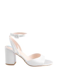 Sandalo bianco con punta aperta, tacco largo e fibbia alla caviglia, caratterizzato da un design minimalista e una fodera interna beige chiaro.