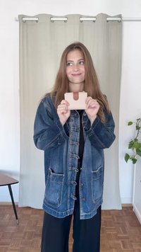 Portafoglio cardholder in pelle beige con accento in pelle marrone, forma rettangolare, esposto con una giacca di jeans su uno sfondo neutro.