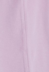 Gros plan d'un tissu violet clair montrant une couture discrète divisant deux panneaux texturés avec un motif fin tissé.